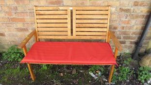 A stained pine two seater garden bench with cushion