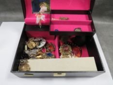 A black jewellery box containing costume jewellery to include bracelets, earrings, and rings