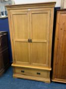 A modern light oak double wardrobe with drawer below