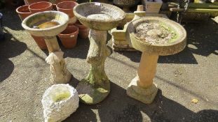 Three concrete bird baths and a hedgehog planter