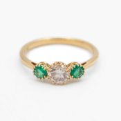 An 18k three-stone diamond and emerald set ring.
