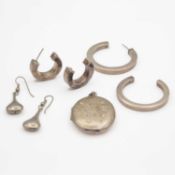 A selection of three silver earrings and a silver locket pendant.