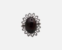 A silver dress ring set with a large oval cabochon dyed black opal, surrounded by melee diamonds.