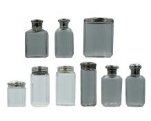 A medley of Victorian and later silver lidded scent bottles and cosmetic jars.