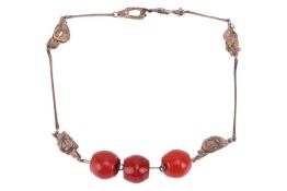 A modernist silver necklace with three barrel-shaped red glass beads, to a chain of elongated bar li