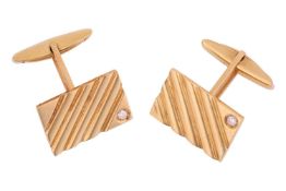 A pair of cufflinks with diamond accents, each comprising a diagonally striated rectangular panel, s