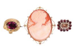 A group of three brooches; The first a stylised belt brooch set with an oval cut purple paste, the b