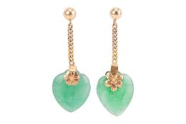 A pair of jade heart drop earrings, each consisting of a carved heart-shaped jadeite, on a flowerhea