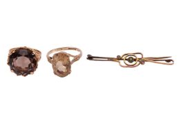 Two rings and a bar brooch, the first a smoky quartz ring, featuring a round-cut smoky quartz measur