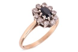 A gem-set cluster ring, composed of an oval dark blue sapphire, surrounded by round-cut cubic zircon