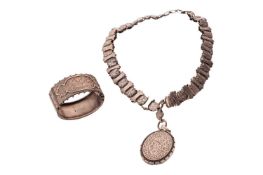 A Victorian silver necklace and bangle. The oval locket with foliate detail, opening to reveal a gla