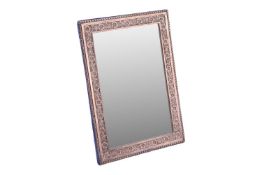 A late Victorian silver-framed table mirror, rectangular with a foliate border and velvet easel back