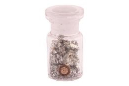 A small glass jar containing white metal nuggets and fragments.