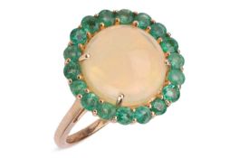 An opal and emerald cluster ring, the central circular cabochon opal, weighing approximately 3.33cts