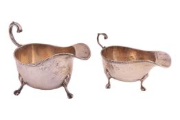 A silver sauce boat, with beaded border, flying double scroll handle and on three ball and claw feet