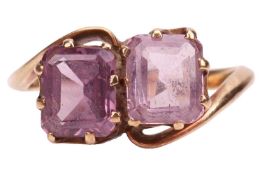 A crossover ring set with two pinkish purple synthetic spinels, claw-set between bypassing shoulders