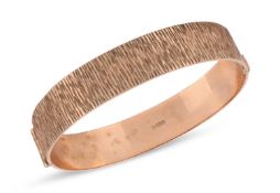 A 9ct yellow gold hinged bangle, of bark textured finish, Birmingham 1971, inner circumference 18.0c