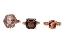 Two smoky quartz dress rings, and a brown topaz dress ring, all set in 9ct yellow gold with British 