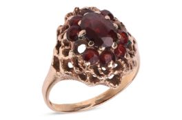 A garnet-set cluster ring, the central oval mixed-cut garnet surrounded by smaller round cut garnets