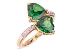 A tsavorite garnet crossover ring in 18ct gold, comprising two heart-shaped tsavorites of deep green