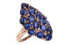 A sapphire dress ring, the lozenge panel, claw-set throughout with oval-shaped synthetic sapphires, 