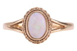 A 9ct gold opal ring, featuring an oval opal cabochon highlighted with twisted wire border, to bifur