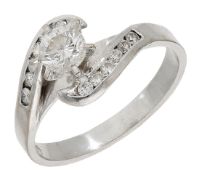 A diamond ring, the brilliant-cut diamond claw-set between crossover shoulders channel-set...