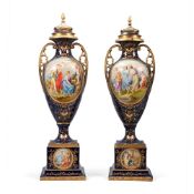 A LARGE PAIR OF BLUE GROUND AND GILT URNS, COVERS AND PLINTH BASES, IN THE VIENNA STYLE, CIRCA 1900