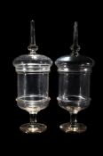 A PAIR OF CLEAR GLASS PEDESTAL CHEMIST JARS AND COVERS