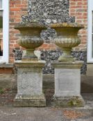 A PAIR OF GEORGE III CARVED COTSWOLD STONE URN PLANTERS, CIRCA 1800
