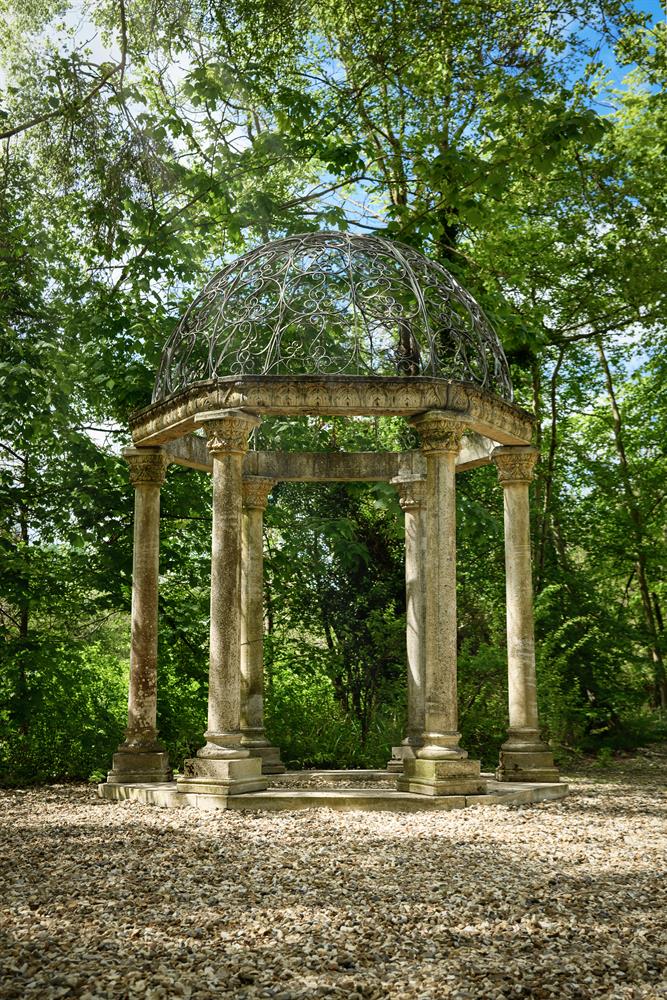 A LARGE WROUGHT IRON MOUNTED COMPOSITION STONE FOLLY OF CLASSICAL ROTUNDA FORM, 20TH CENTURY