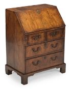 A GEORGE II WALNUT AND FEATHERBANDED BUREAU OF SMALL PROPORTIONS, CIRCA 1730
