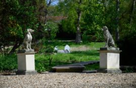A PAIR OF COMPOSITION STONE MODELS OF SEATED HOUNDS ON PLINTHS, CONTEMPORARY