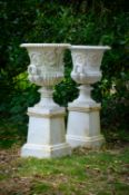 A PAIR OF HANDYSIDE WHITE PAINTED CAST IRON URNS ON STANDS, 19TH CENTURY