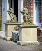 A PAIR OF CARVED LIMESTONE SEATED DOGS WITH BASKETS, EARLY 20TH CENTURY