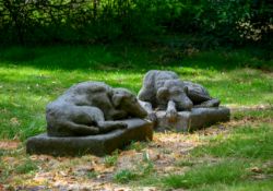 A PAIR OF COMPOSITION STONE RECUMBENT GREYHOUNDS, 20TH CENTURY