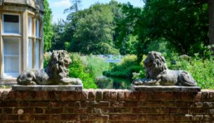 A PAIR OF COMPOSITION STONE LIONS, AFTER THE MODEL BY COADE, EARLY 20TH CENTURY