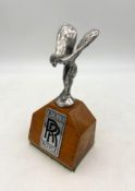 A Rolls-Royce Silver Shadow Spirit Of Ecstacy Mascot Mounted on a polished wood plinth with
