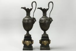 pair of neoclassical ornamental bronze jugs, each on a base with gilded Hermès heads