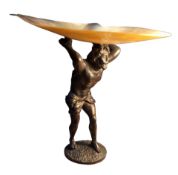 A dark patinated figural bronze stand, of Hercules, he stands holding a mother-of-pearl shell aloft,