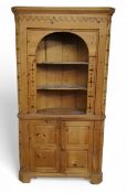 A pine floor-standing corner cabinet, moulded cornice with raised swags, pierced borders and splays,