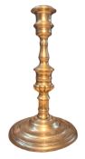 A '16th' century style brass candlestick, reel shaped nozzle, knopped stem, spreading circular base,