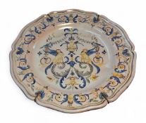 An Italian faience earthenware shaped circular plate, decorated in tones of yellow, blue and brown