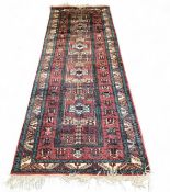 A Persian Karaja runner, with four medallions and geometrical border, in red, black and beige, 275cm
