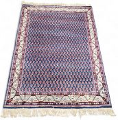 A Persian Sarouk woollen rug, with repeating paisley (boteh) in deep blue and red, 160cm x 107cm