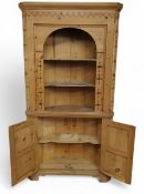 A pine floor-standing corner cabinet, moulded cornice with raised swags, pierced borders and splays,