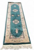 A Chinese woollen runner, with  floral mons and sprigs on a green ground, 244cm x 75cm, c.1930