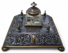 A Victorian brass and copper square inkwell and pen stand, the border cast in relief with figures,