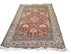 A Persian style woollen rug, with central medallion, stylised foliage and birds on a red ground,