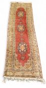 A Turkish Kayseri woollen runner, with three medallions on a red and cream ground, 222cm x 60cm